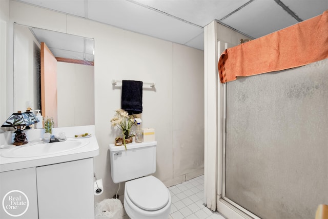 bathroom with tile patterned flooring, vanity, toilet, and a shower with door