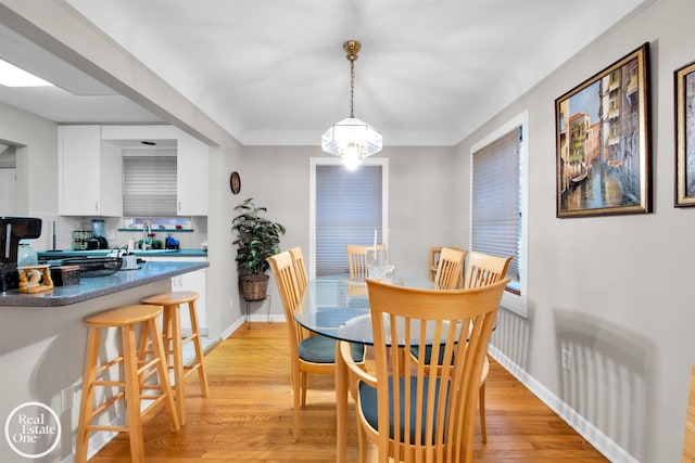 dining space with light hardwood / wood-style floors and a notable chandelier