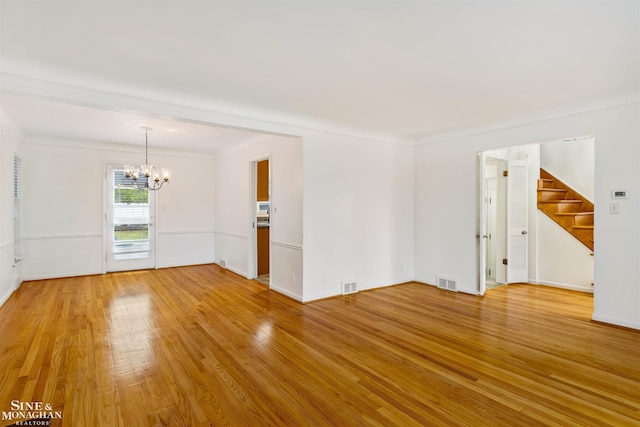 spare room featuring hardwood / wood-style flooring, ornamental molding, and a notable chandelier