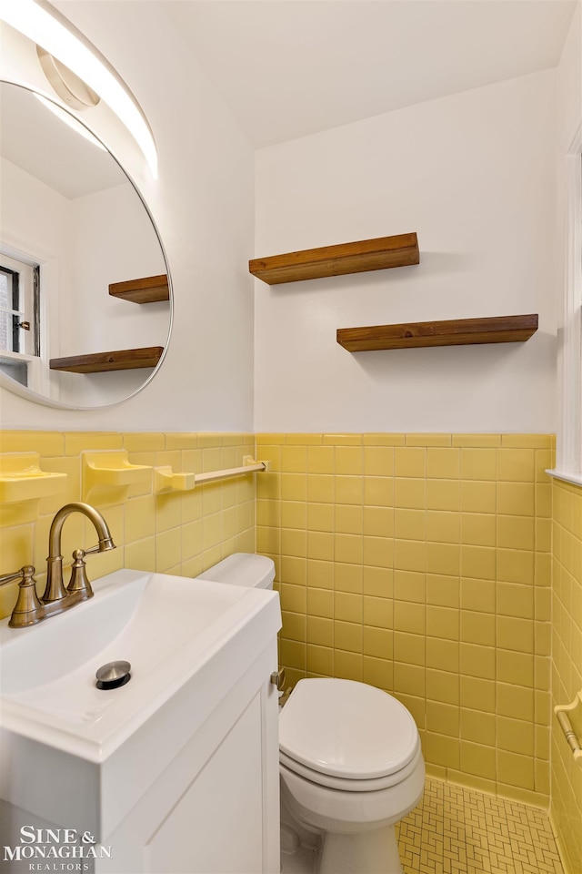 bathroom with tile patterned flooring, vanity, toilet, and tile walls