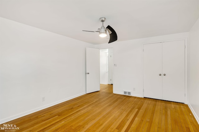 unfurnished bedroom with ceiling fan, light wood-type flooring, and a closet