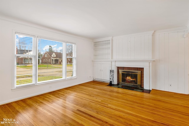 unfurnished living room featuring light hardwood / wood-style flooring and a brick fireplace