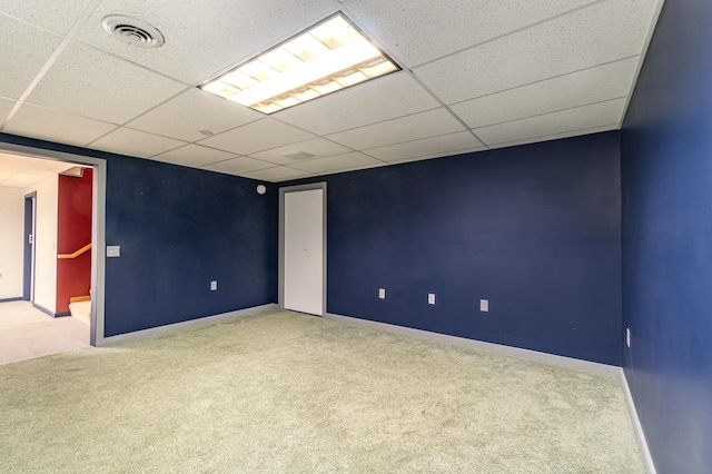 carpeted empty room featuring a drop ceiling