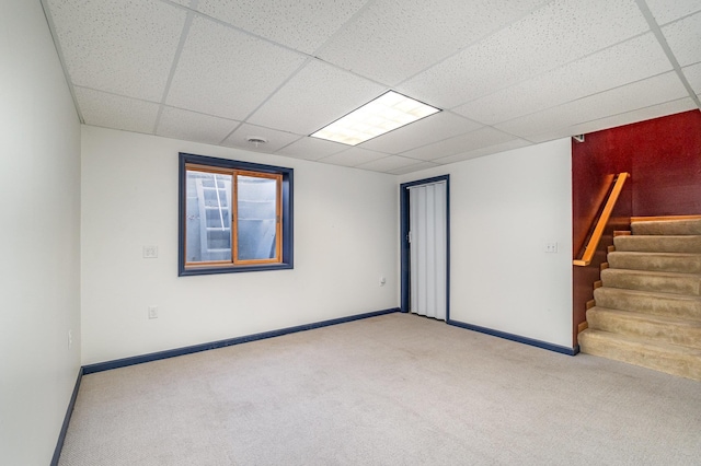 unfurnished room featuring a drop ceiling and light colored carpet