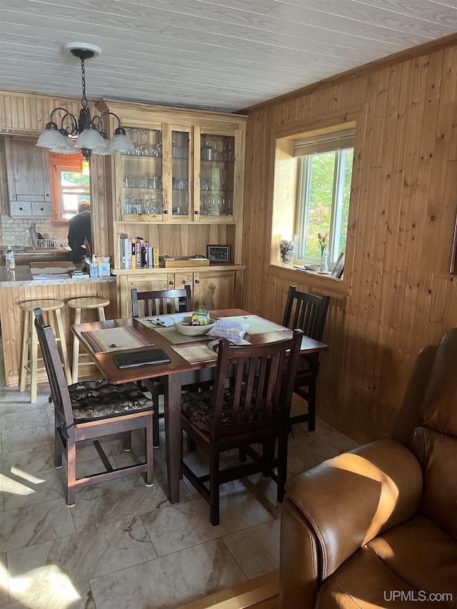 dining room with a chandelier, wooden ceiling, and wood walls