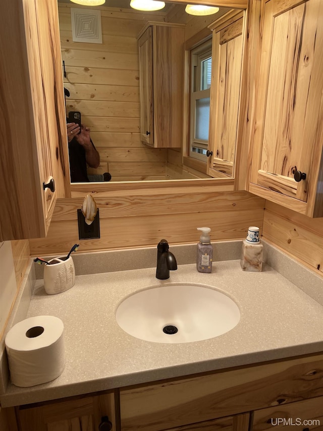 bathroom featuring wooden walls and vanity