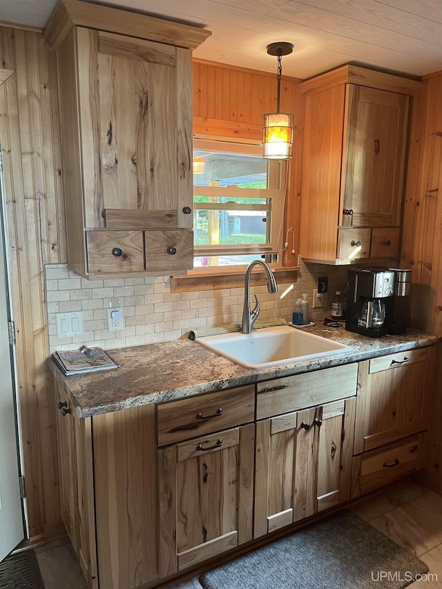 kitchen with backsplash, sink, hanging light fixtures, light tile patterned floors, and stone countertops