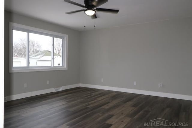 empty room featuring baseboards, dark wood finished floors, and a ceiling fan