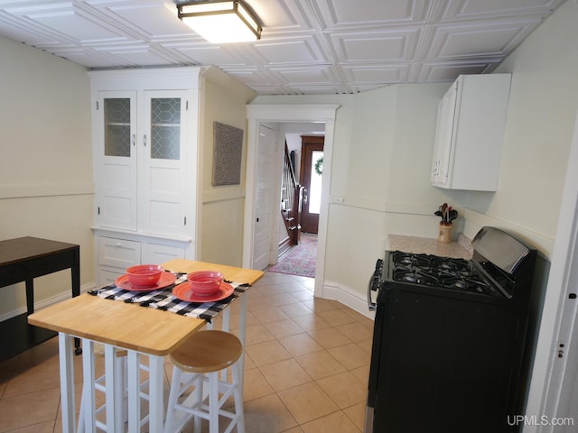 kitchen with black gas range, white cabinets, and light tile patterned floors