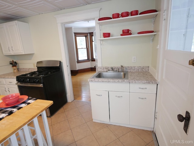 kitchen featuring sink, white cabinetry, black gas range oven, and light tile patterned floors