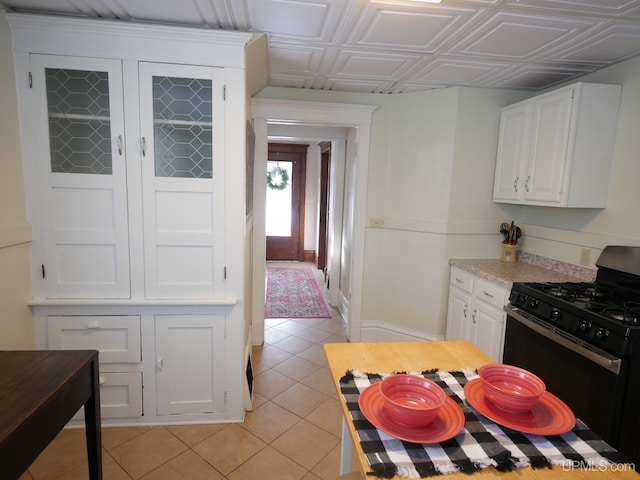 kitchen featuring gas stove, white cabinets, and light tile patterned floors