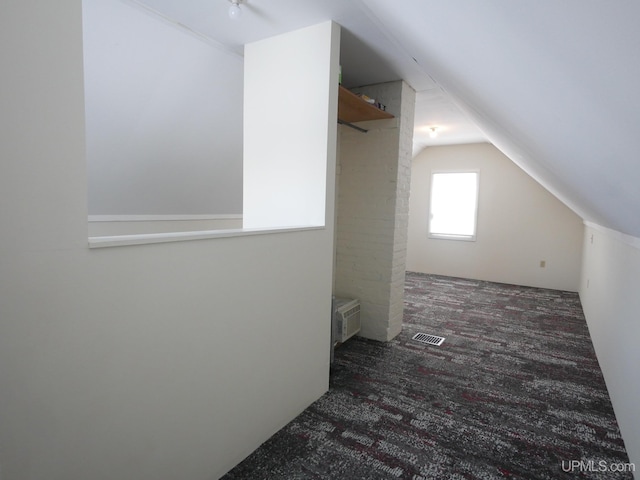 bonus room featuring dark carpet, vaulted ceiling, and an AC wall unit