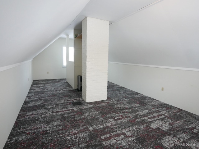 additional living space featuring dark carpet and vaulted ceiling