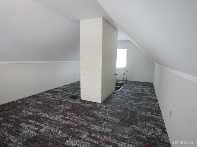 bonus room with dark carpet and lofted ceiling