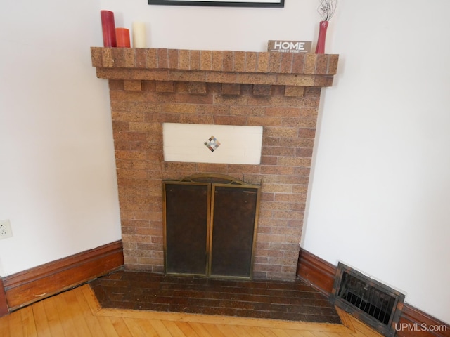 interior details with wood-type flooring and a brick fireplace