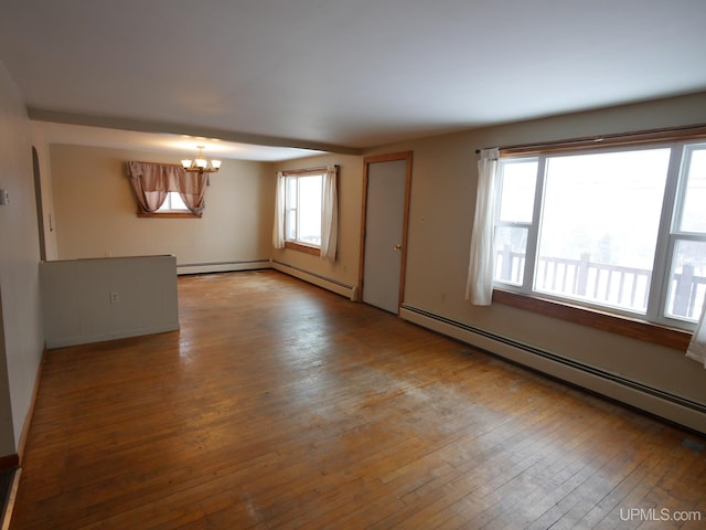 empty room with a wealth of natural light, light hardwood / wood-style flooring, baseboard heating, and a notable chandelier