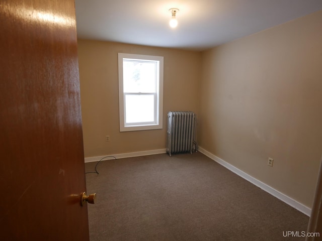 empty room with carpet flooring and radiator heating unit