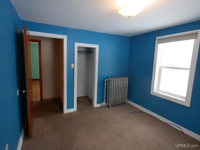 unfurnished bedroom featuring carpet flooring, radiator heating unit, and a closet