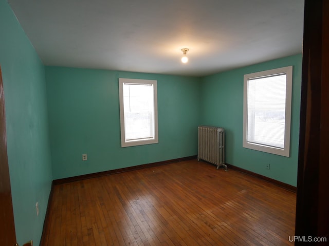 spare room featuring radiator heating unit and dark hardwood / wood-style floors