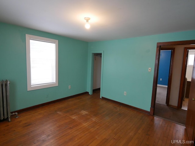 unfurnished bedroom featuring dark hardwood / wood-style flooring, a closet, and radiator heating unit