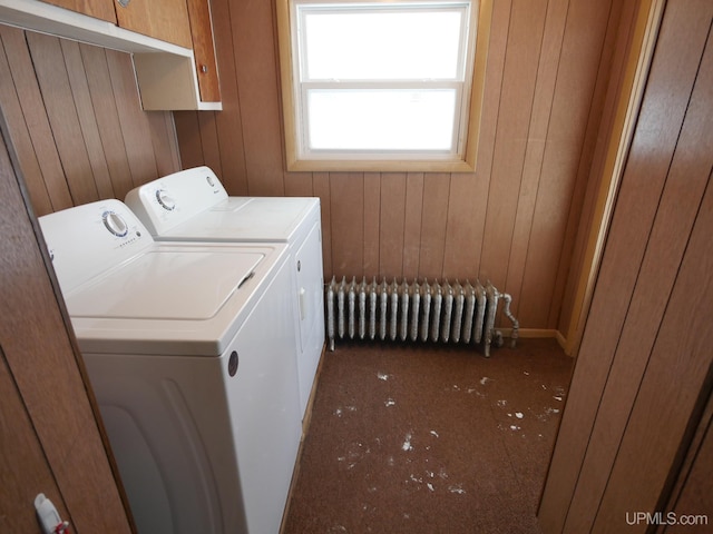 laundry room featuring radiator, wood walls, and washing machine and clothes dryer