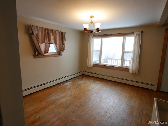 empty room with a chandelier, hardwood / wood-style floors, and a baseboard heating unit