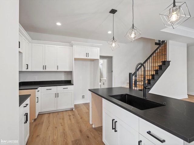 kitchen featuring white cabinets, pendant lighting, light hardwood / wood-style floors, and sink