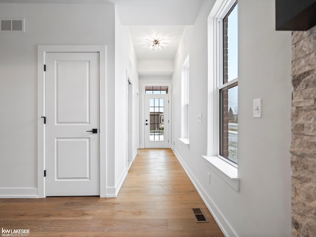 corridor with light wood-type flooring and a wealth of natural light