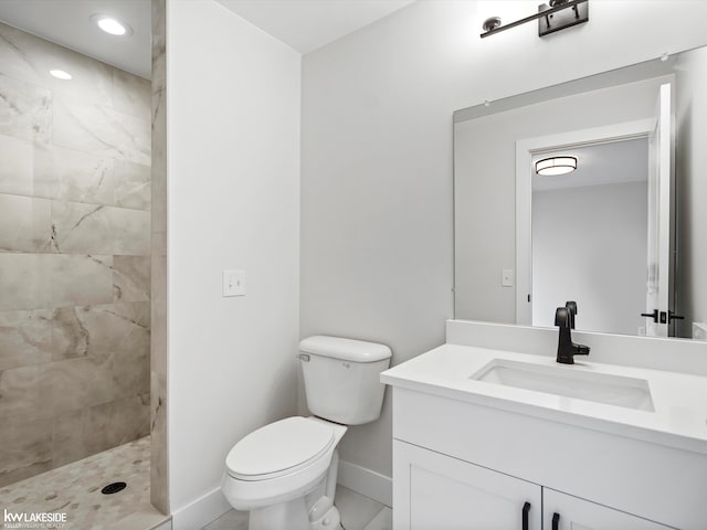 bathroom featuring a tile shower, vanity, and toilet