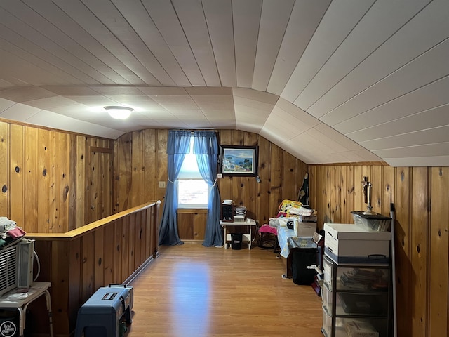 additional living space featuring wood walls, lofted ceiling, and light wood-type flooring