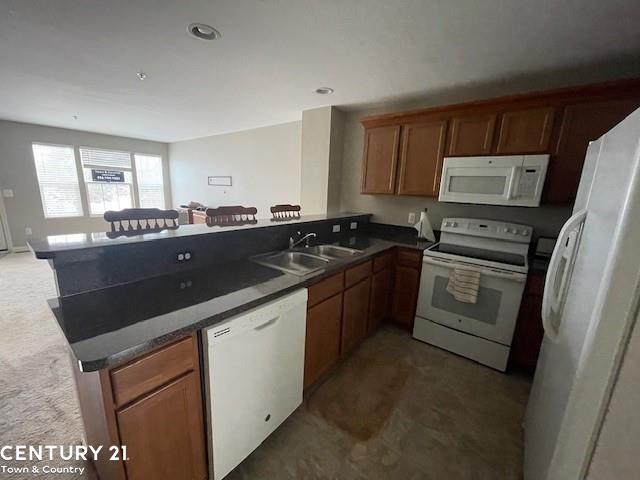 kitchen featuring kitchen peninsula, sink, white appliances, and dark carpet