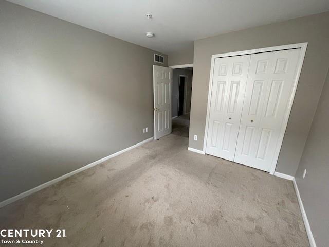 unfurnished bedroom featuring a closet and light carpet