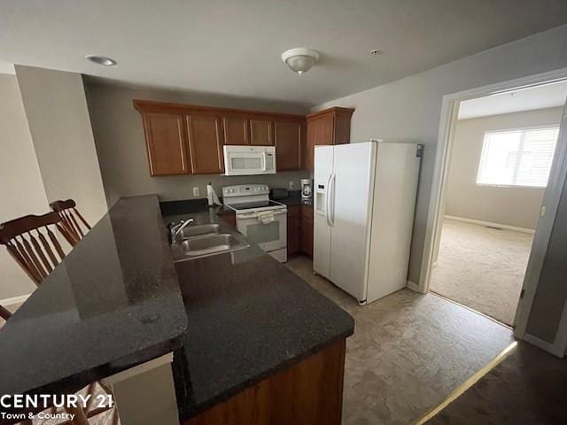 kitchen with sink, kitchen peninsula, dark carpet, and white appliances