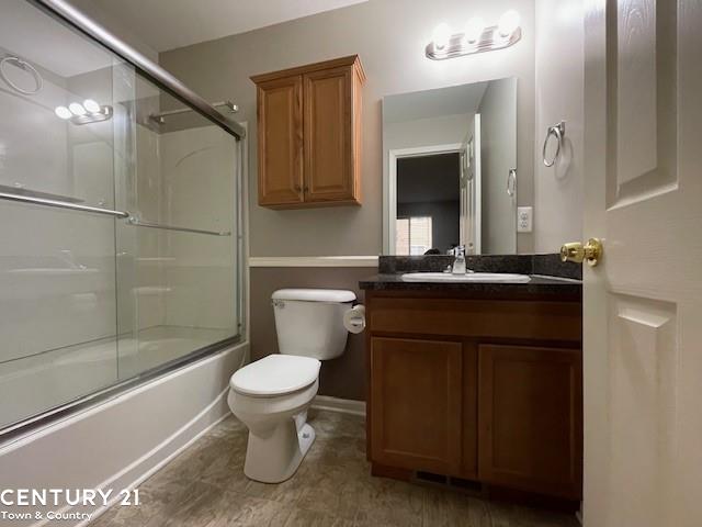 full bathroom with toilet, vanity, and shower / bath combination with glass door