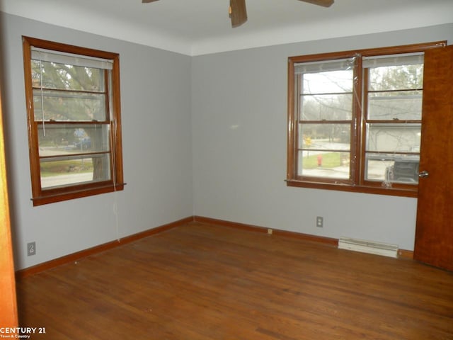 empty room with baseboard heating and dark hardwood / wood-style floors