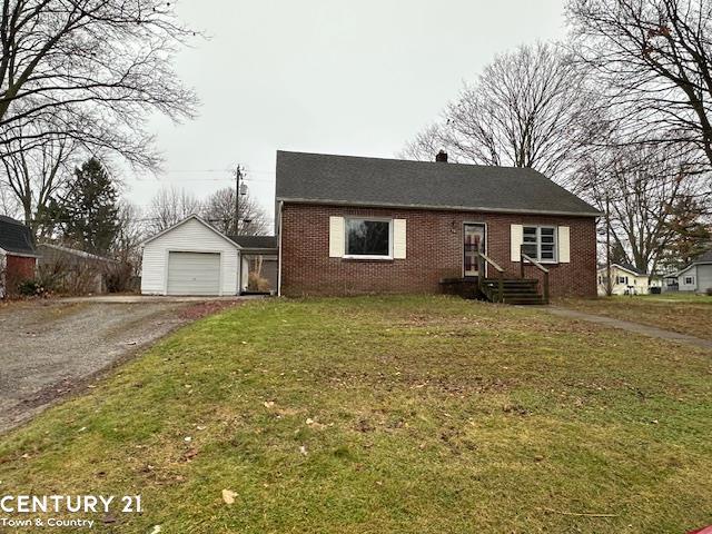 view of front of home with a garage, an outbuilding, and a front lawn