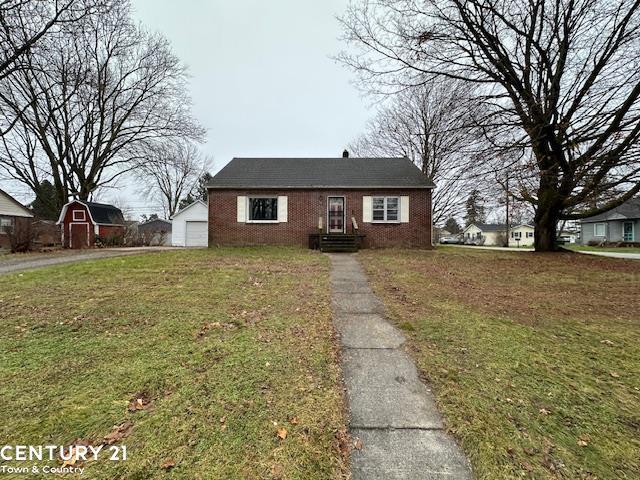 bungalow-style house featuring an outbuilding, a garage, and a front yard