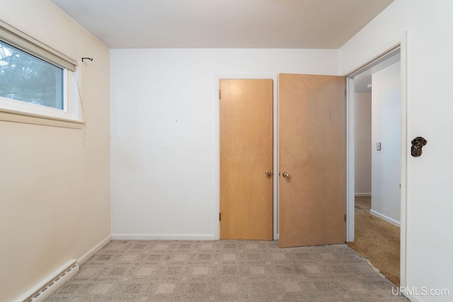 unfurnished bedroom featuring light carpet, a baseboard radiator, and a closet