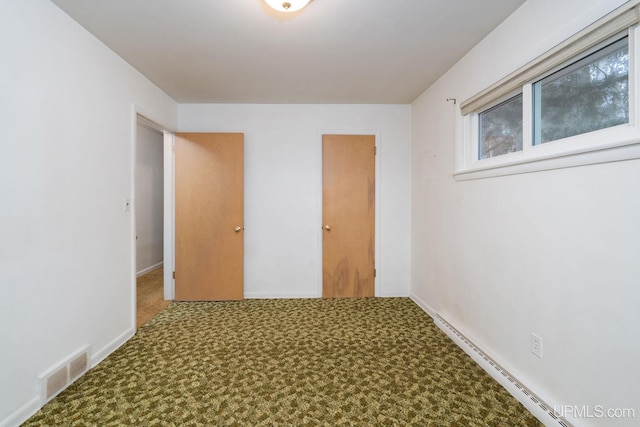 unfurnished room with carpet floors and a baseboard heating unit