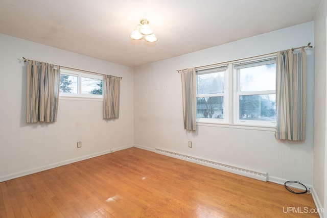 spare room with hardwood / wood-style flooring and a baseboard heating unit