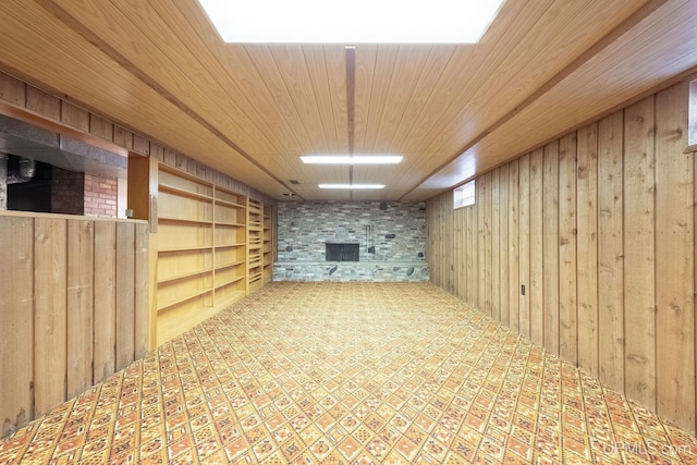 basement featuring wooden ceiling, a fireplace, and wooden walls