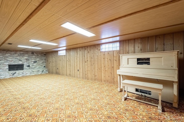 basement featuring a stone fireplace, wooden walls, and wooden ceiling