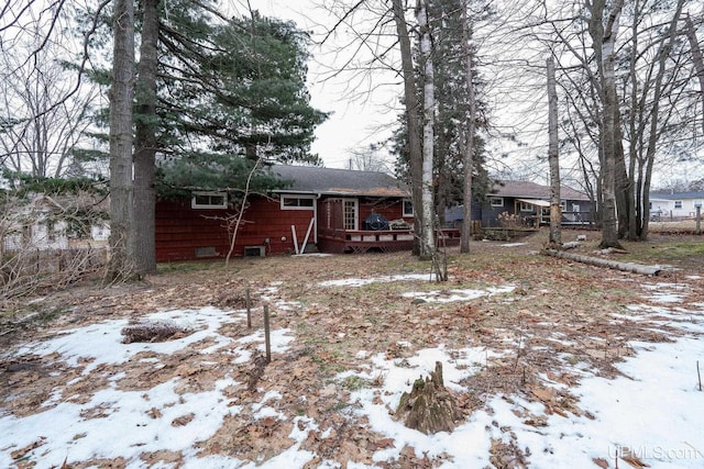 snow covered rear of property with a wooden deck