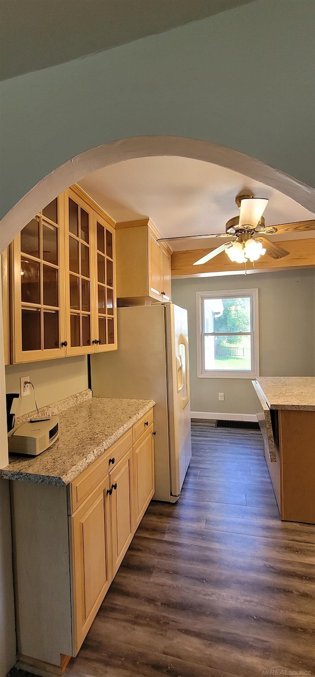 kitchen with white fridge, light stone counters, ceiling fan, and dark wood-type flooring