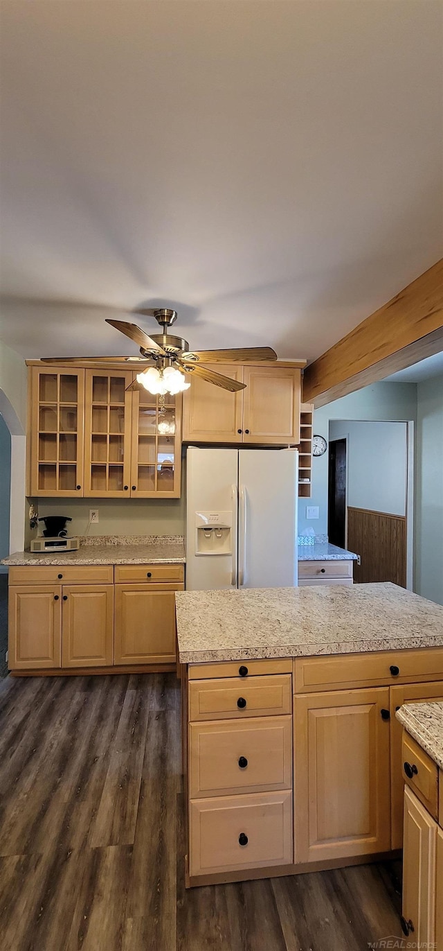 kitchen featuring light brown cabinets, dark wood-type flooring, light stone countertops, white fridge with ice dispenser, and a kitchen island