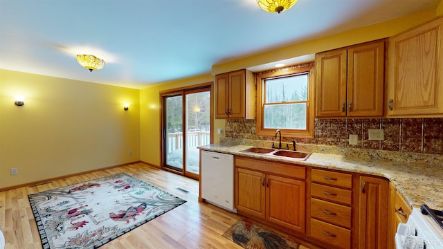 kitchen featuring light stone countertops, sink, light hardwood / wood-style flooring, white dishwasher, and range