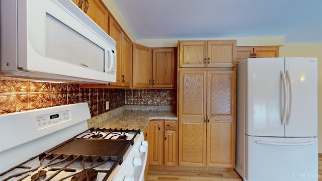 kitchen featuring light stone countertops, white appliances, and tasteful backsplash