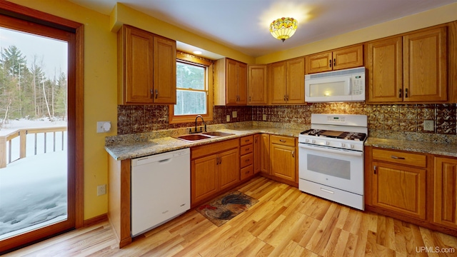 kitchen featuring white appliances, light hardwood / wood-style flooring, light stone counters, and sink