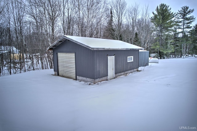 snow covered structure featuring a garage