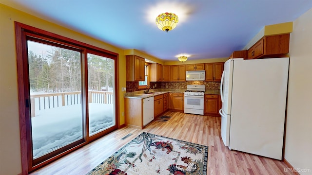 kitchen with light wood-type flooring, white appliances, backsplash, and sink